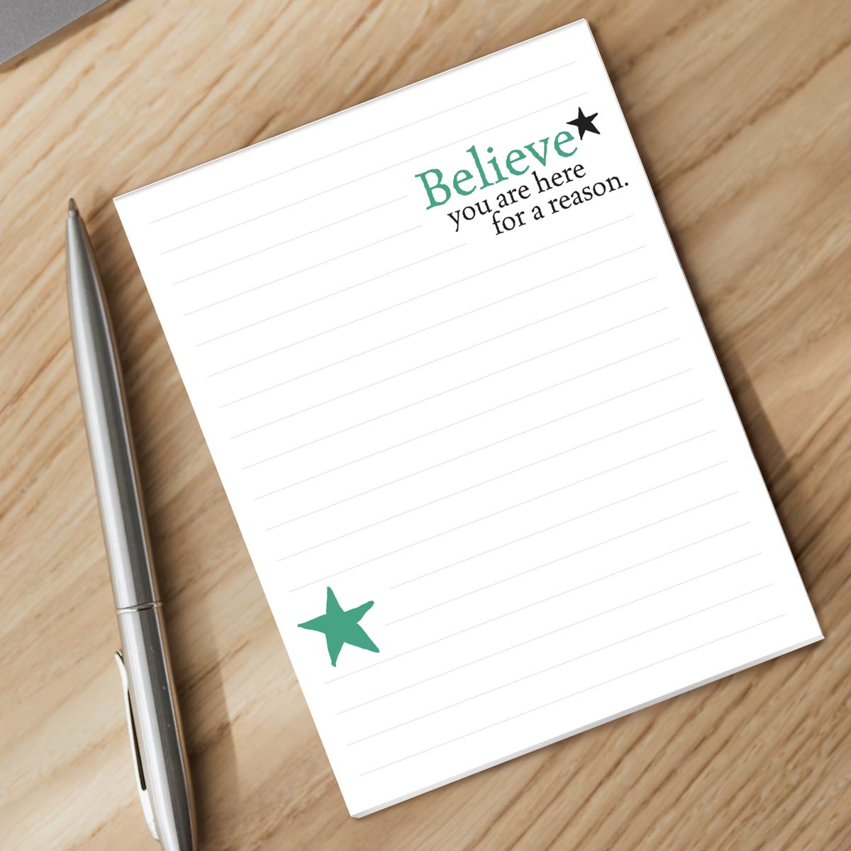 believe notepad and silver pen sitting on a desk