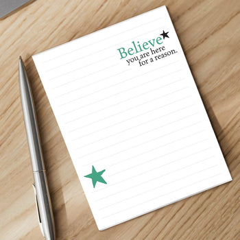 believe notepad and silver pen sitting on a desk
