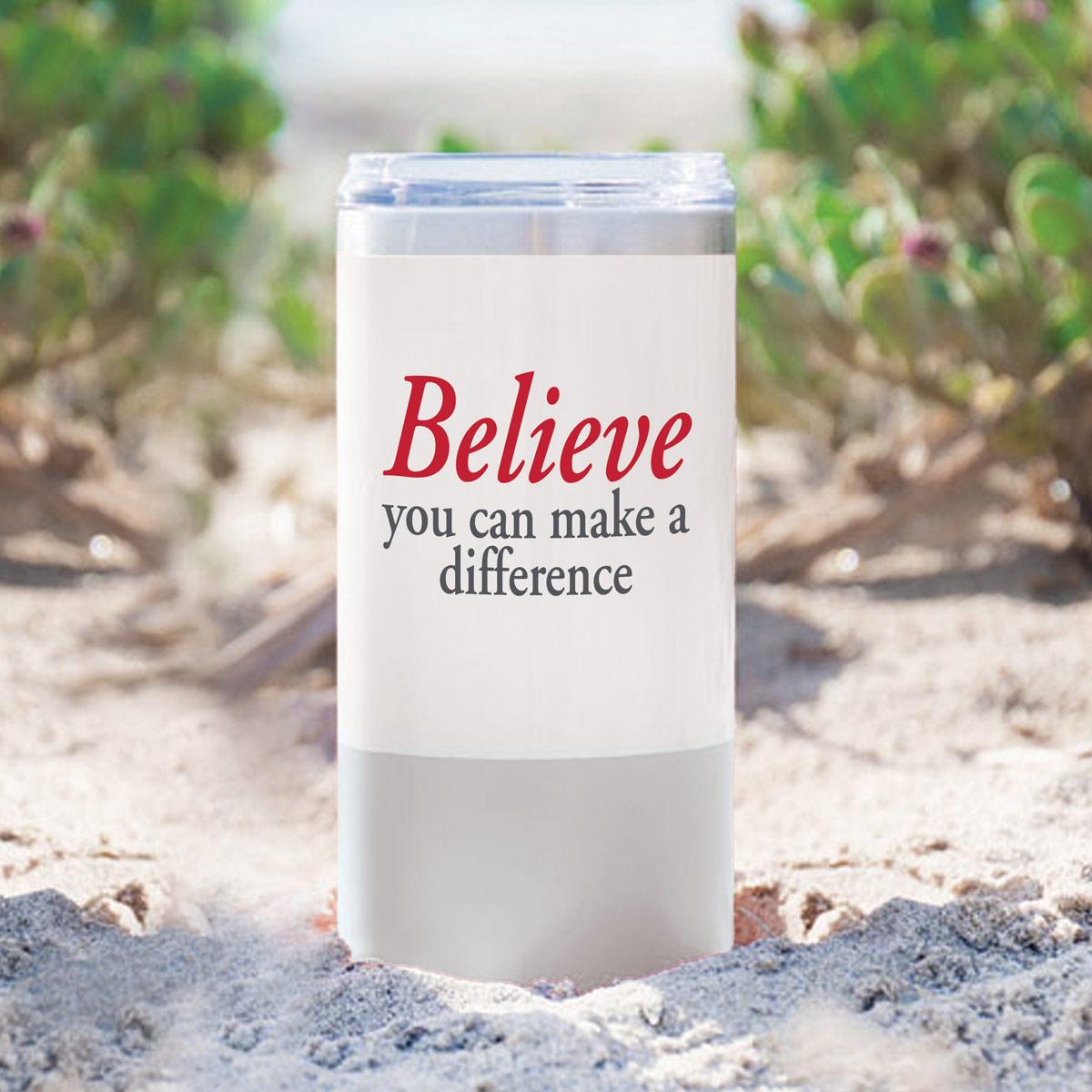 white and grey stainless steel tumbler with believe message sitting in sand