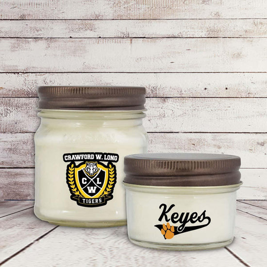 two white candles in glass jars with custom logos