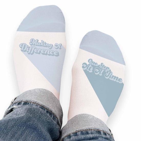 Pair of no-show socks with a black heel and a colorful Making A Difference message on top.