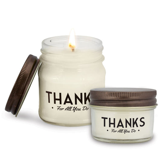 two white candles in glass jars with thanks message