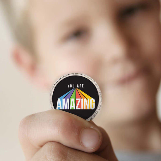 a boy holding a you are amazing coin