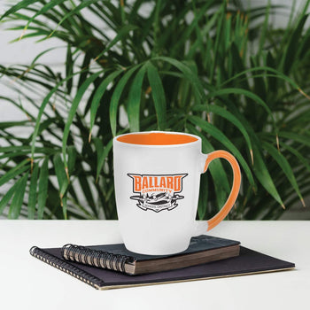 ceramic mug with orange handle and custom logo sitting on a desk