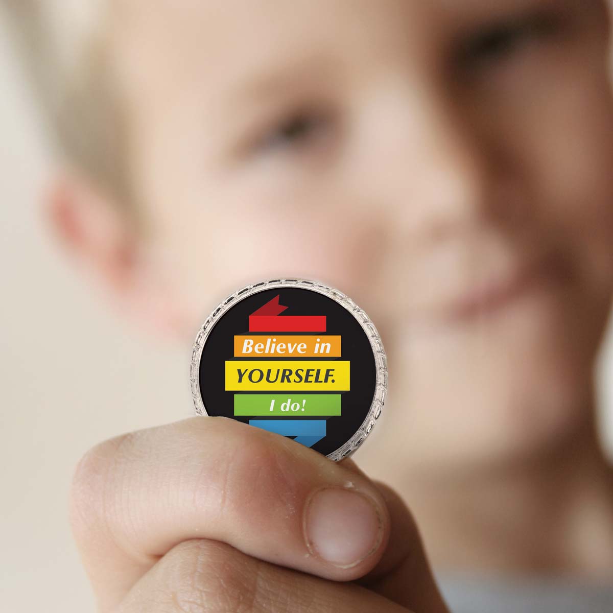 a boy holding a believe in yourself coin