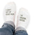 Pair of no-show socks with a black heel and a message on top; I can’t get up right now I’m grading papers.