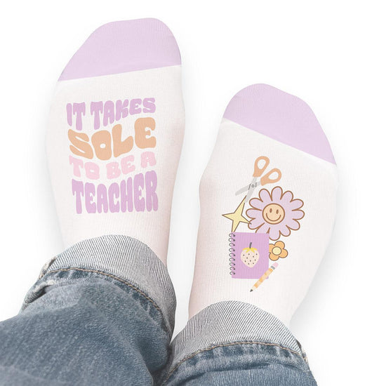 Pair of no-show socks with a black heel and a colorful It Takes Sole To Be A Teacher message on top.
