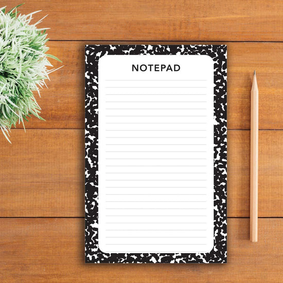 large college ruled composition notepad with pencils sitting on a table