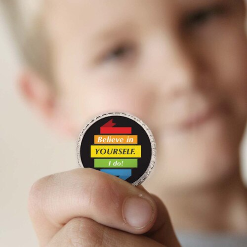 a boy holding a believe in yourself coin