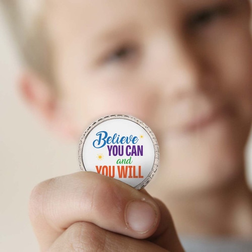 a boy holding a believe you can coin
