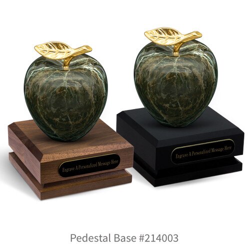 black and a brown walnut pedestal bases with black brass plates and green marble apples