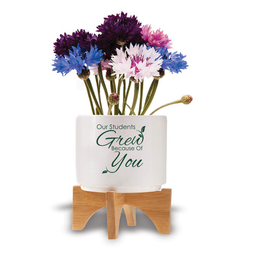 Two-piece bamboo stand with modern white ceramic planter featuring the inspirational message “Our Students Grew Because Of You.” Grows a patriotic mix of flowers.