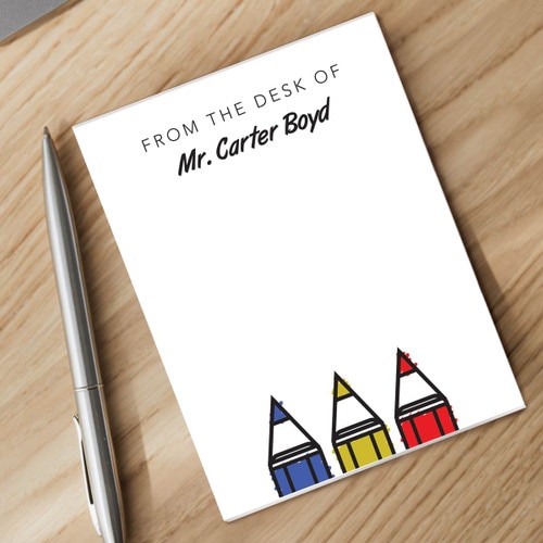 primary color pencils notepad and silver pen sitting on a desk