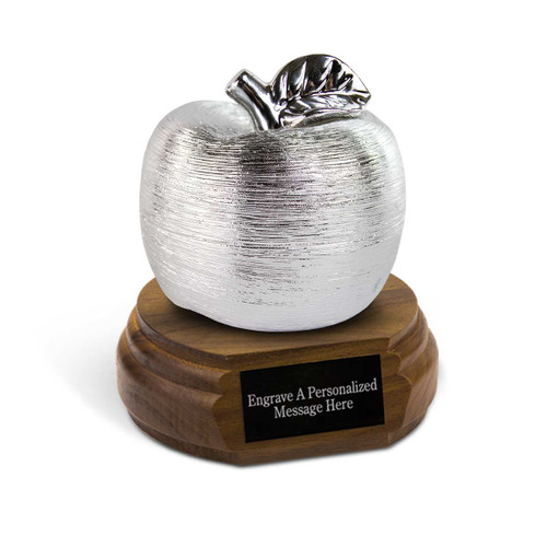 silver spun ceramic apple sitting on top a walnut base with black brass plate