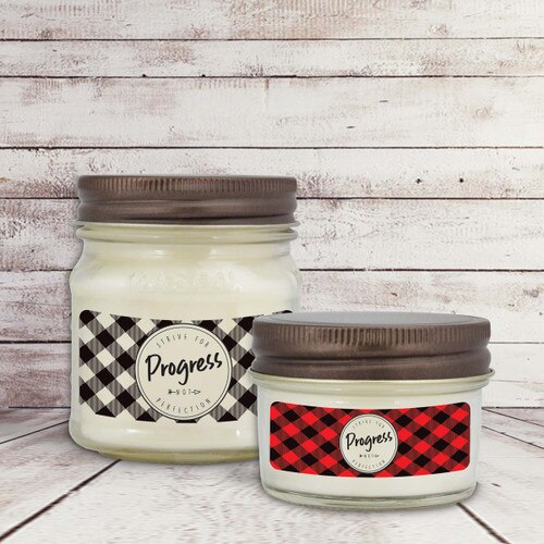 two white candle in glass jar with strive for progress message