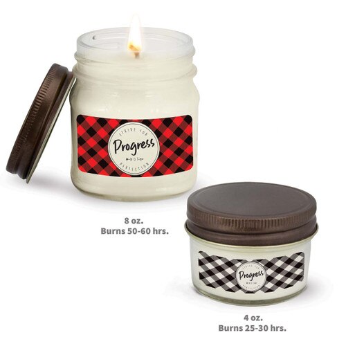 two white candle in glass jar with strive for progress message