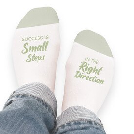Pair of no-show socks with a black heel and a colorful Success Is Small Steps In The Right Direction message on top.