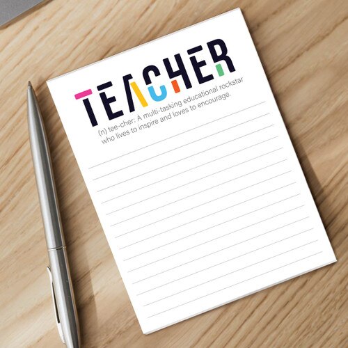 tee-cher notepad and silver pen sitting on a desk